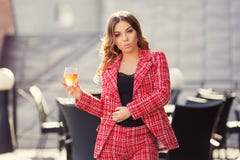 Young fashion woman in red tweed jacket and shorts suit at sidewalk cafe royalty free stock photography Young fashion woman in red tweed jacket and shorts suit at sidewalk cafe royalty free stock photography
