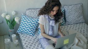 Young fashionable blogger writes a new article on a laptop sitting in bed. stock video Young fashionable blogger writes a new article on a laptop sitting in bed. stock video