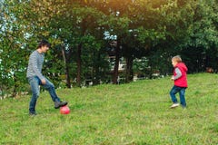 Young Father With His Little Son Playing Football On Green Grassy Lawn. Stock Photos