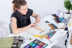 Young female artist drawing sketch using sketchbook with pencil at her workplace in studio. Side view portrait of stock photos Young female artist drawing sketch using sketchbook with pencil at her workplace in studio. Side view portrait of stock photos