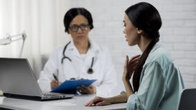 Young female patient saying symptoms, experienced doctor keeping medical records stock image Young female patient saying symptoms, experienced doctor keeping medical records stock image