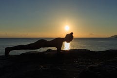 Young female silhouette doing plank exercise on a beach at sunrise royalty free stock photo Young female silhouette doing plank exercise on a beach at sunrise royalty free stock photo