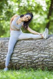 Young fit beautiful girl resting and stretching on a tree log stock image Young fit beautiful girl resting and stretching on a tree log stock image