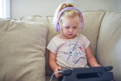 Child with headphones sitting on couch alone with laptop tablet royalty free stock images Child with headphones sitting on couch alone with laptop tablet royalty free stock images