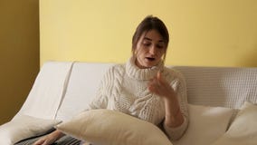 A young girl in a cozy warm sweater on a winter evening at home, reading a book and falling asleep stock video footage A young girl in a cozy warm sweater on a winter evening at home, reading a book and falling asleep stock video footage