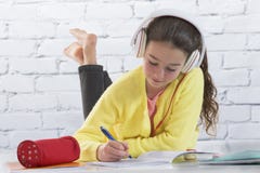 Young girl with headset doing homework on floor stock photo Young girl with headset doing homework on floor stock photo