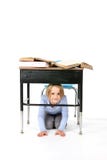 Young Girl Hiding Under A School Desk Royalty Free Stock Image