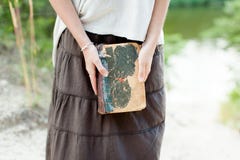 A young girl is holding a very old shabby book in her hands. Sum Stock Photos A young girl is holding a very old shabby book in her hands. Sum Stock Photos
