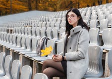 Young Girl In A Gray Coat Sits On A Seat Of An Empty Stadium Royalty Free Stock Photos Young Girl In A Gray Coat Sits On A Seat Of An Empty Stadium Royalty Free Stock Photos
