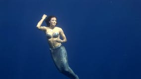 Young girl model underwater seamaiden costume on blue background in Red Sea.