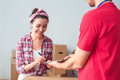 Young girl moving to new place standing signing receipt on digital tablet with delivery man smiling satisfied royalty free stock photos Young girl moving to new place standing signing receipt on digital tablet with delivery man smiling satisfied royalty free stock photos