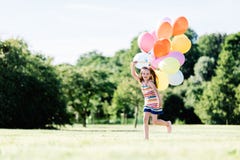 Young girl running on the grass field with balloons. stock image Young girl running on the grass field with balloons. stock image