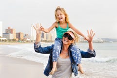 Young girl sitting on mom`s shoulder while walking on beachfront royalty free stock images Young girl sitting on mom`s shoulder while walking on beachfront royalty free stock images