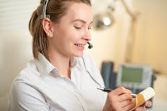 A young girl works in a call center. For a working place. Recording data. On the earphone with a microphone. Telecommunication. stock photos A young girl works in a call center. For a working place. Recording data. On the earphone with a microphone. Telecommunication. stock photos