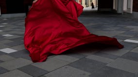 Young gorgeous woman in long red dress walking in the city