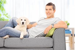 Young guy sitting on couch with a puppy at home royalty free stock photos Young guy sitting on couch with a puppy at home royalty free stock photos