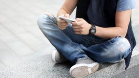 A young guy uses his smartphone while sitting on the asphalt. royalty free stock photos A young guy uses his smartphone while sitting on the asphalt. royalty free stock photos
