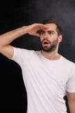 A young guy in a white T-shirt on a black background looks into the distance royalty free stock photos A young guy in a white T-shirt on a black background looks into the distance royalty free stock photos