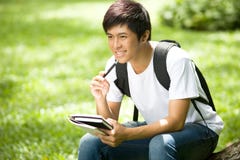 Young handsome Asian student with books and smile in outdoor