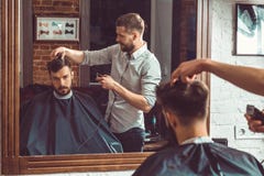 Young handsome barber making haircut of attractive man in barbershop royalty free stock image Young handsome barber making haircut of attractive man in barbershop royalty free stock image