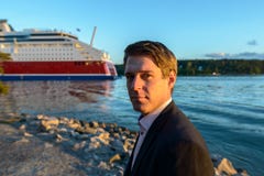Young handsome businessman standing in beautiful scenic shore with cruiseline in the river