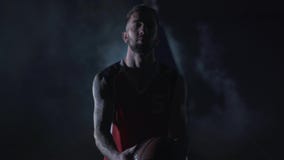 Portrait young handsome brutal unshaved confident basketball player stand with a ball in the clouds of smoke on black stock footage Portrait young handsome brutal unshaved confident basketball player stand with a ball in the clouds of smoke on black stock footage