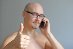 Young handsome man in black glasses is talking on the phone. Closeup portrait of a man. A man shows thumb up. Everything is great royalty free stock photography Young handsome man in black glasses is talking on the phone. Closeup portrait of a man. A man shows thumb up. Everything is great royalty free stock photography