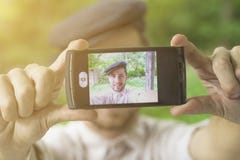 Young handsome man with cap taking self with phone stock image Young handsome man with cap taking self with phone stock image