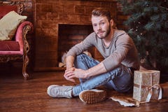 A young handsome man looking at a camera while sitting on a floor surrounded by gifts royalty free stock photo A young handsome man looking at a camera while sitting on a floor surrounded by gifts royalty free stock photo
