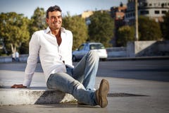 Young Handsome Man Smiling Sitting On The Ground On Sidewalk Street. Outdoor Royalty Free Stock Photos