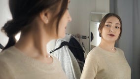 Young and happy brunette female in clothes store smiling and choosing new things stock video Young and happy brunette female in clothes store smiling and choosing new things stock video