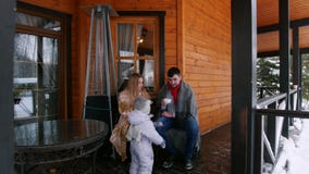 Young happy family with a little baby drinking hot drinks on the veranda of a beautiful house stock video footage Young happy family with a little baby drinking hot drinks on the veranda of a beautiful house stock video footage