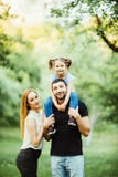Young happy family of three having fun together outdoor. Pretty little daughter on her father back. Father carrying daughter piggy stock image Young happy family of three having fun together outdoor. Pretty little daughter on her father back. Father carrying daughter piggy stock image