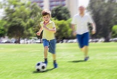Young happy father and excited 7 or 8 years old son playing together soccer football on city park garden running on grass kicking royalty free stock photos Young happy father and excited 7 or 8 years old son playing together soccer football on city park garden running on grass kicking royalty free stock photos