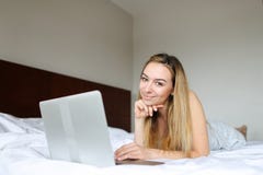Young happy female person using laptop and lying on bed in morning. stock photography Young happy female person using laptop and lying on bed in morning. stock photography