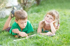 young happy kids, children reading books on natural backgrou
