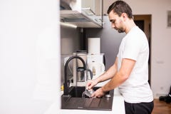 Young happy man doing the dishes smiling confident and relaxed enjoying doing domestic work in fun and positive male housework dut royalty free stock photos Young happy man doing the dishes smiling confident and relaxed enjoying doing domestic work in fun and positive male housework dut royalty free stock photos