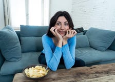 Lifestyle portrait of cheerful young woman sitting on the couch watching TV holding remote control stock images Lifestyle portrait of cheerful young woman sitting on the couch watching TV holding remote control stock images