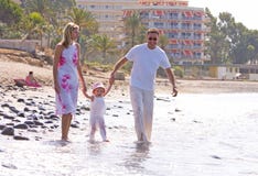 Young, healthy family walking along a sunny beach