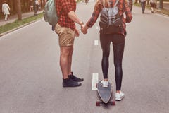 Young hipster couple. Guy teaches his girlfriend to skateboard on the street in a park. stock photography Young hipster couple. Guy teaches his girlfriend to skateboard on the street in a park. stock photography