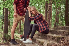 Young hipster couple, handsome man and blonde girl with a skateboard, sitting on steps in a park. royalty free stock images Young hipster couple, handsome man and blonde girl with a skateboard, sitting on steps in a park. royalty free stock images