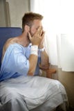 Young injured man crying in hospital room sitting alone crying in pain worried for his health condition stock photo Young injured man crying in hospital room sitting alone crying in pain worried for his health condition stock photo