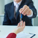 Young lady taking keys from male real estate agent during meeting after signing rental lease contract or sale purchase royalty free stock photo Young lady taking keys from male real estate agent during meeting after signing rental lease contract or sale purchase royalty free stock photo