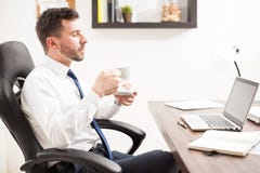 Young lawyer drinking coffee in his office. Profile view of a good looking young lawyer enjoying a cup of coffee in his office while reading some emails royalty free stock photo Young lawyer drinking coffee in his office. Profile view of a good looking young lawyer enjoying a cup of coffee in his office while reading some emails royalty free stock photo