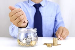 Young man depositing money in glass jar royalty free stock photo Young man depositing money in glass jar royalty free stock photo