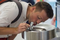 A young man is drinking water from a free fountain at the airport. Royalty Free Stock Images A young man is drinking water from a free fountain at the airport. Royalty Free Stock Images