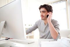 Young Man Having A Call In Front Of Computer Royalty Free Stock Photography