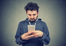 Young man holding smartphone being upset with text message royalty free stock photography Young man holding smartphone being upset with text message royalty free stock photography