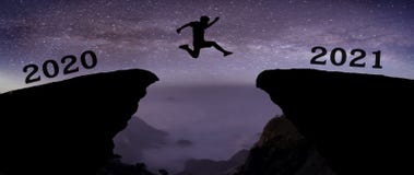 A young man jump between 2020 and 2021 years over night sky with stars and through on the gap of hill silhouette evening colorful