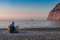 Young man with laptop working on the beach. Freedom, remote work, freelancer, technology, internet, travel and vacation concepts stock image Young man with laptop working on the beach. Freedom, remote work, freelancer, technology, internet, travel and vacation concepts stock image